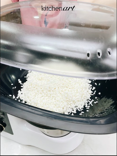 Trộn gạo với muối hồng, rải đều lên khay hấp.